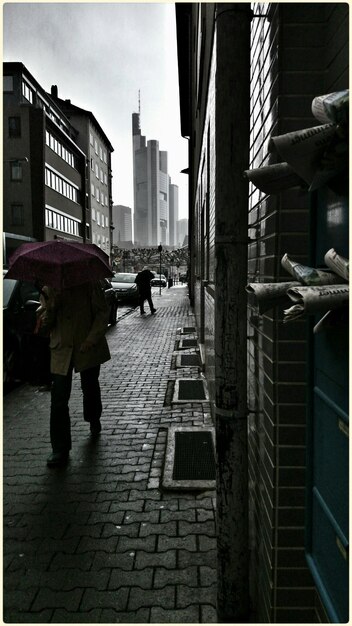 Photo man walking under umbrella on cobblestone street