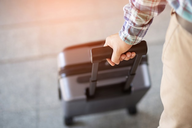 Photo man walking with luggage. traveler pulling suitcase, closeup view