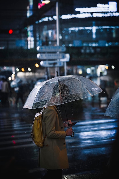 Uomo che cammina con un ombrello trasparente in una città di notte