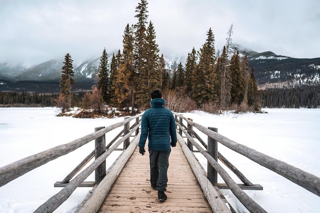 A man walking on wooden bridge among frozen lake in Pyramid Lake on winter at Jasper national park