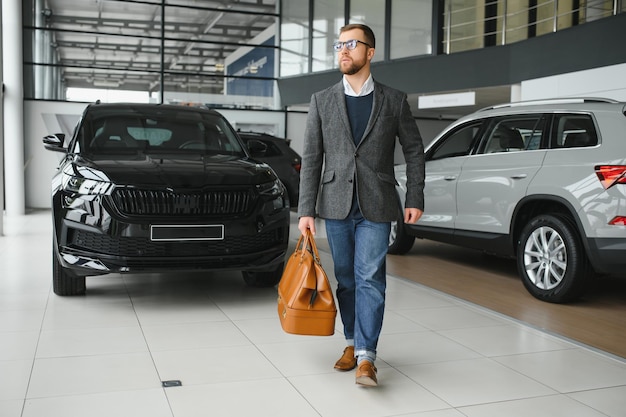 A man walks around a car dealership and chooses a new car