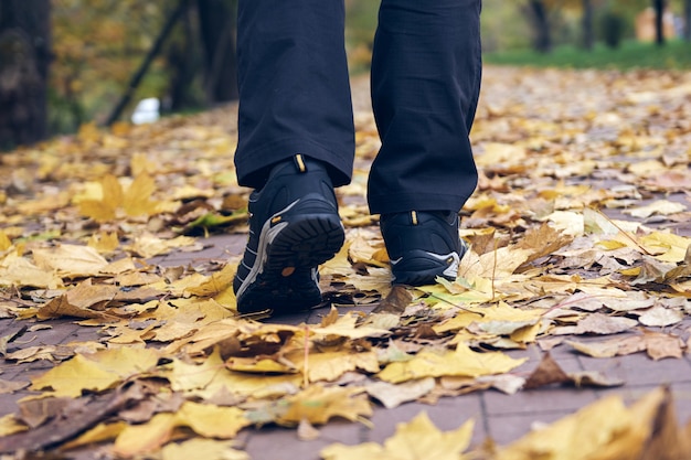 Man walks in autumn park. Top View of hiking Boot. Close-up Legs In J sport trekking shoes in the forest