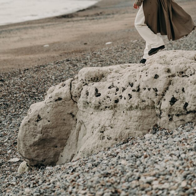 한 남자가 커다란 모래 조각상을 들고 해변을 걷고 있다.