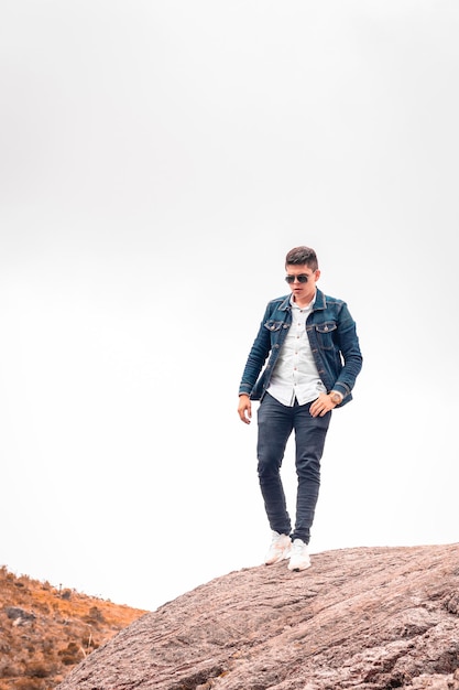 Man walks down a mountain wearing sunglasses with clouds