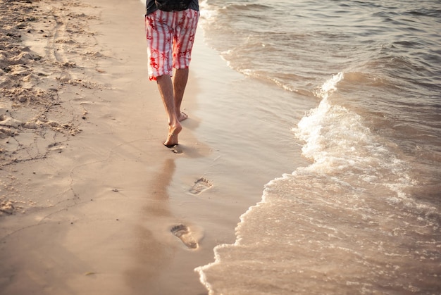 A man walks on the sand on vacation in the sunset