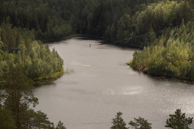 A man walks on a slackline over a picturesque forest lake