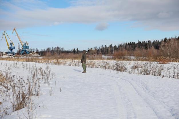 A man walks on a snowy forest road