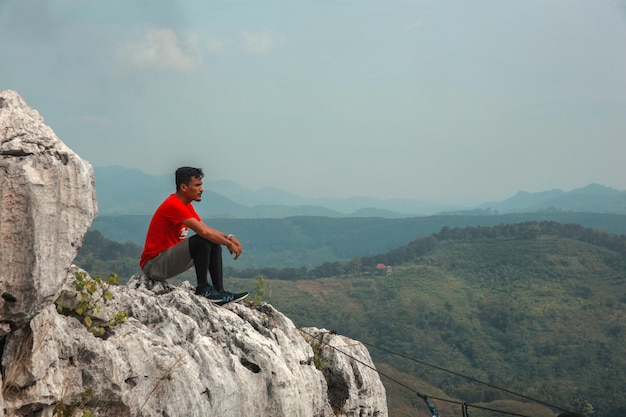 man wandelaar zittend op de top heuvel en genieten van een prachtig uitzicht op de heldere blauwe lucht
