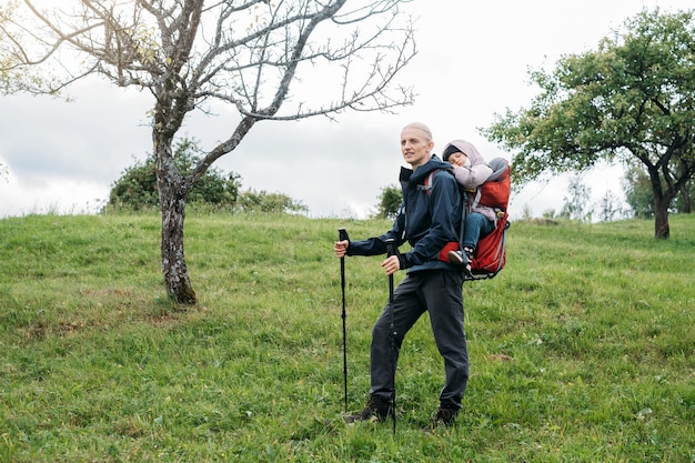 Man wandelen met slaperig peuterkind in rugzak in de bergen