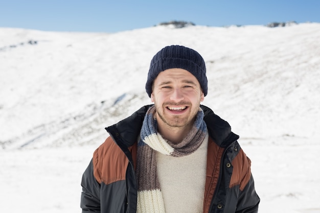 暖かい服を着た男、雪の多い風景に立っている