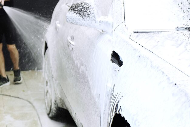 Man washes a brown car at a car wash Coated with car foam Closeup of the front fender with dripping foam Car detailing