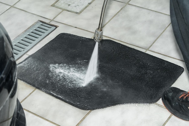 Man washes the car mats with soap and water with a pressure washer