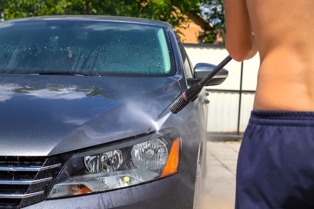 A man washes his car on the street