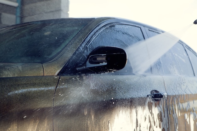 男が車を水で洗う