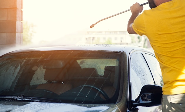 A man washes his car with water