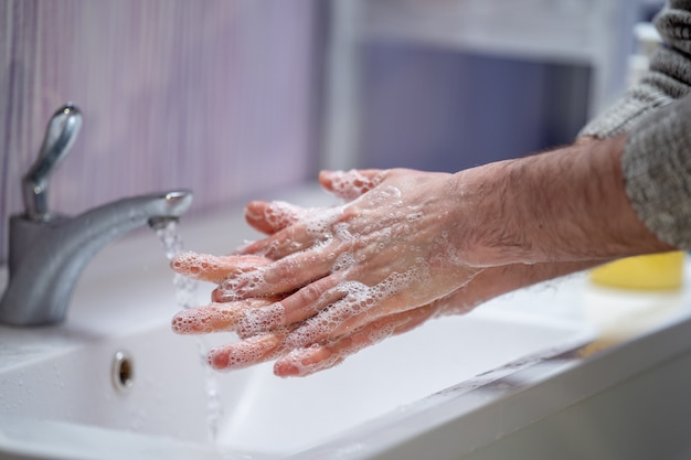 男は自宅で石鹸で手を洗います。概念ウイルス保護。手指衛生。