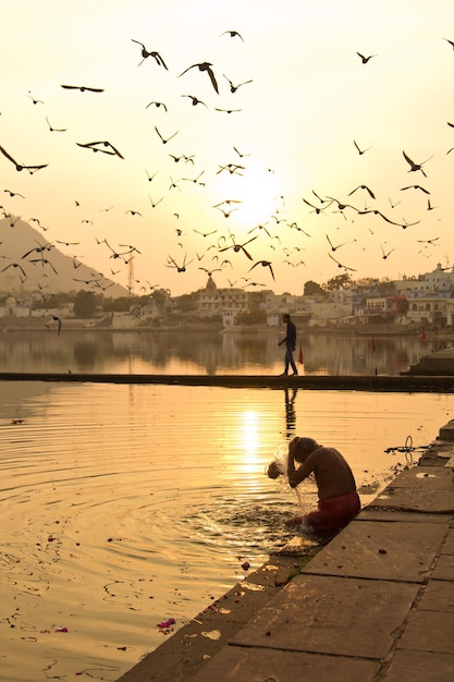 A man washes his head in the water at sunset Pushkar lake India