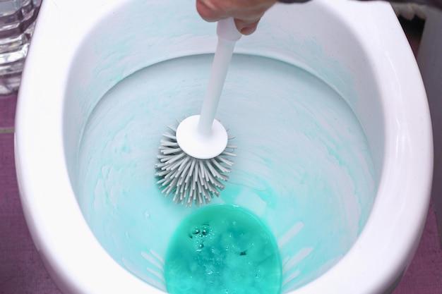 A man washes the toilet with a silicone brush and cleaner cleaning of the house bathroom