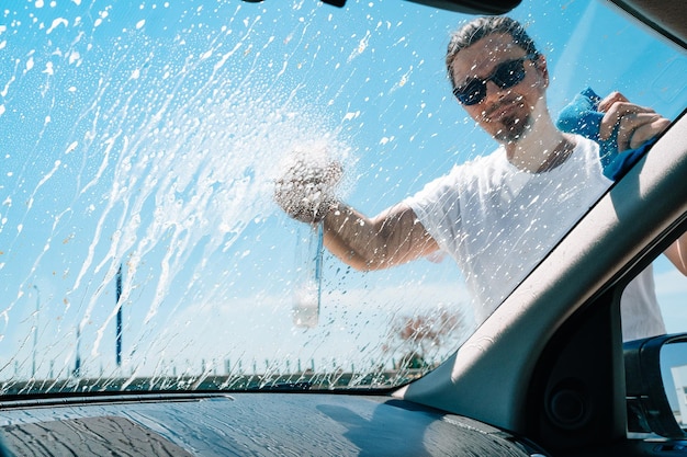 車のフロントガラスを洗っている男