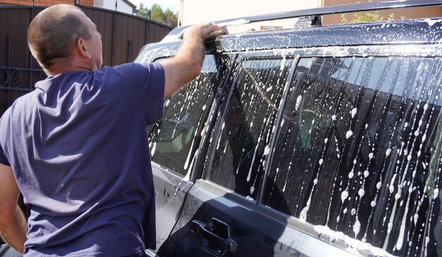 Photo man washing car with car wash pressure washer shampoo sponges and microfiber car towels