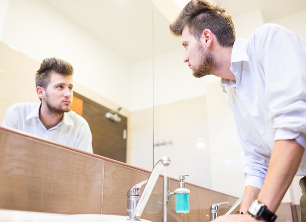 Foto uomo che lava la faccia in bagno