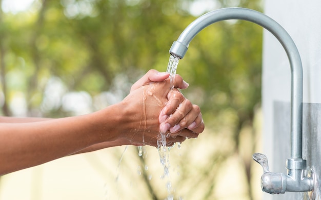 Man washing hand after working with outdoor faucet sink, cleaning hygiene protection concept