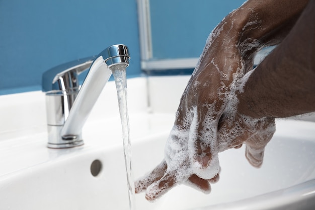 Man washing hands carefully with soap and sanitizer, close up. Prevention of pneumonia virus spreading, protection against coronavirus pandemia. Hygiene, sanitary, cleanliness, disinfection. Safety.