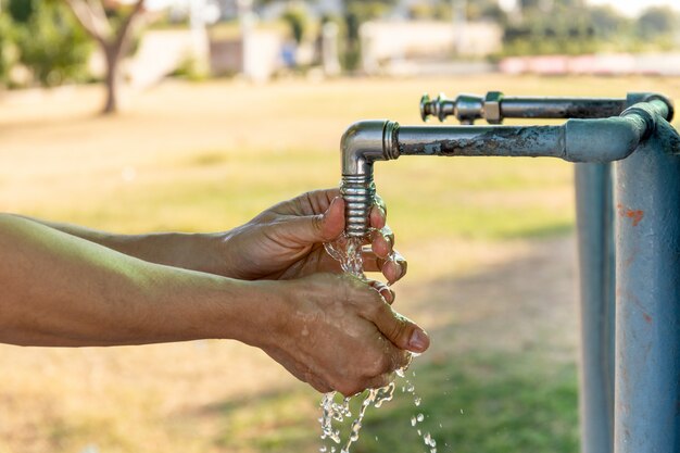 Man washing hands from plumbing tap outdoor.