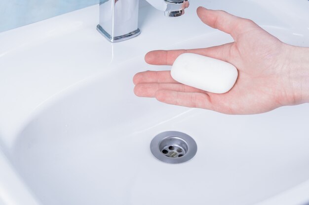 man washing hands with soap in bathroom