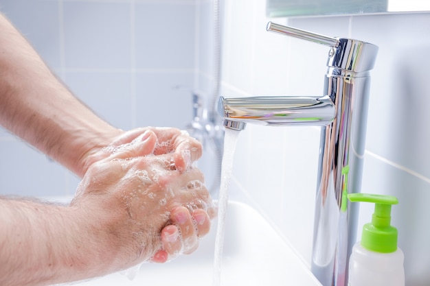 バスルームに石鹸で手を洗う人