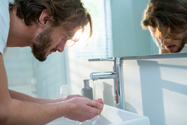 Man washing his face with water in bathroom