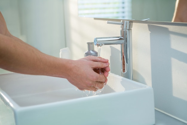 Uomo che si lava le mani nel lavandino del bagno