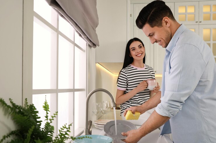 फोटो man washing plate and talking with woman in kitchen