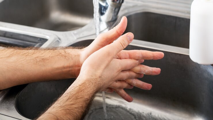 Foto man wast handen in metalen gootsteen met zeep. blanke man handen wassen. handhygiëne, gezondheidszorg, desinfectie medisch concept. handhuid desinfectie beschermen tegen coronavirus covid 19. lange webbanner