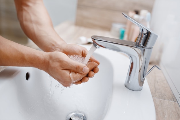 Man wast zijn gezicht in de badkamer, routine ochtendhygiëne.