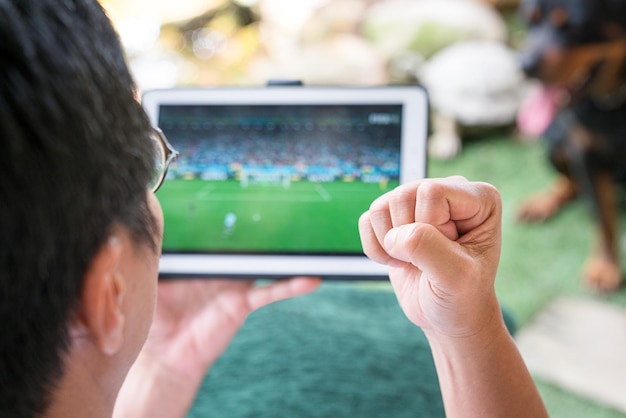 Foto uomo che guarda il gioco di sport di calcio sulla tavoletta digitale