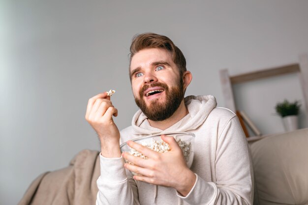 自宅のソファに座って映画を見ている男