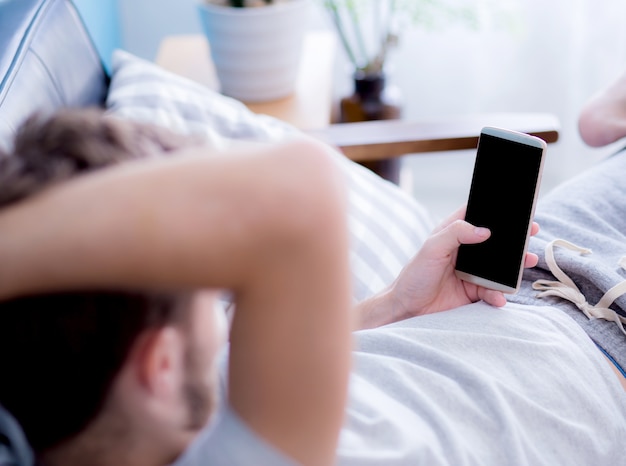 Man watching a smartphone sitting on a couch