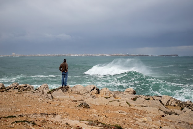 Man watching on winter ocean and city Peniche, Portugal