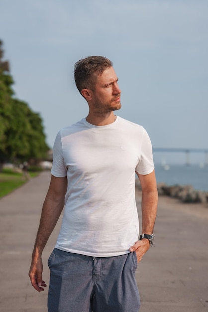 man on waterfront walkway with bridge and boats in background