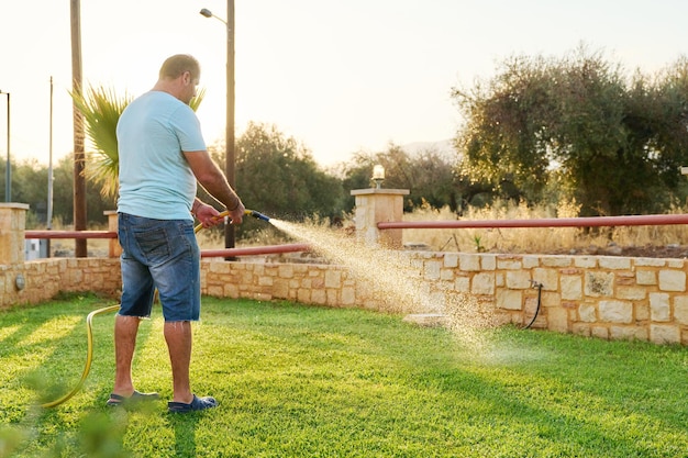 Man watering the lawn with a hose in the morning