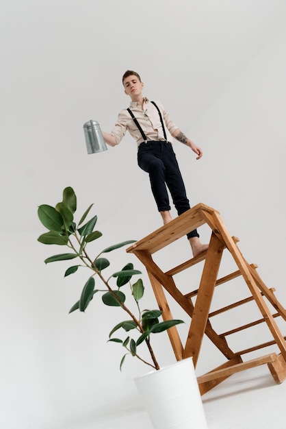 Photo man watering plant while standing on ladder against white background