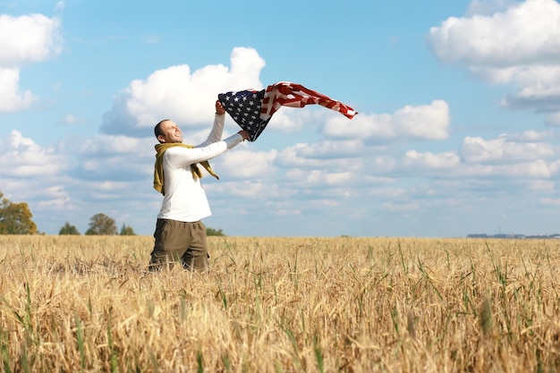 Man waving American flag standing in grass farm agricultural field , holidays, patriotism, pride, freedom, political parties, immigrant