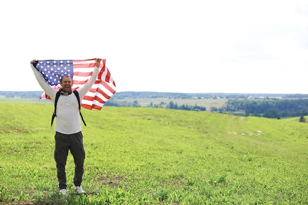 Man waving American flag standing in grass farm agricultural field , holidays, patriotism, pride, freedom, political parties, immigrant