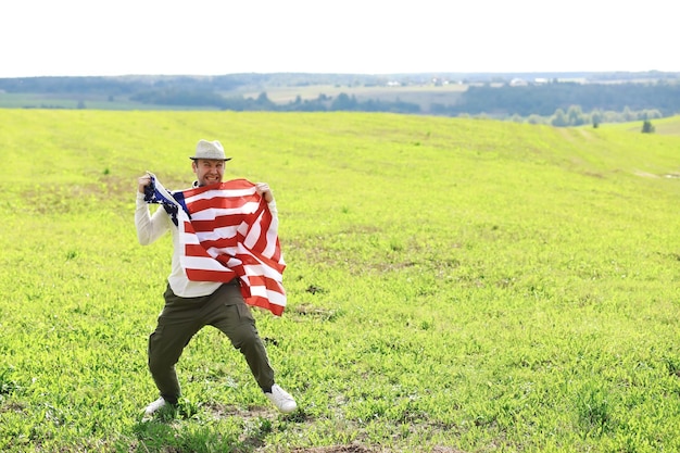 Man waving american flag standing in grass farm agricultural\
field holidays patriotism pride freedom political parties\
immigrant