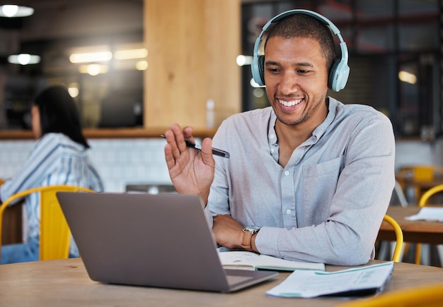 Man waving hands to greet hello on video call online chat and virtual meeting with laptop webcam in a cafe Happy freelance journalist and remote worker in conversation and internet communication