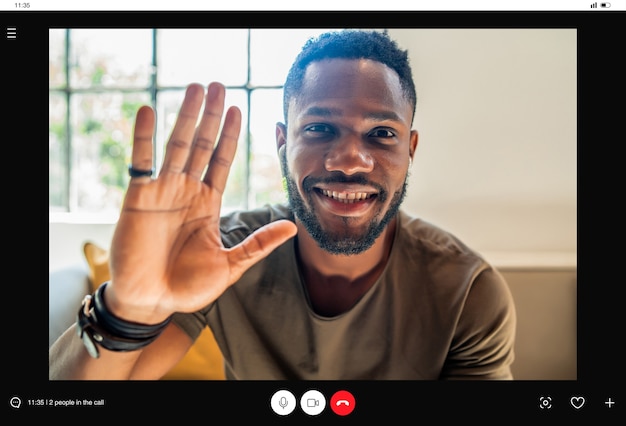 Photo man waving his hand and saying hello to someone while having a video call at home. new normal lifestyle concept.