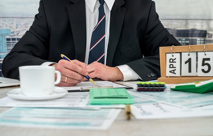 Man wear black suit filling 1040 tax form and using calculator in office