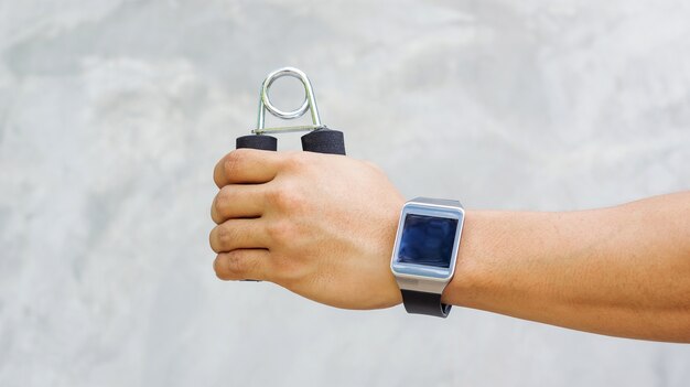 Man wear a smartwatch and use handgrips for exercise.