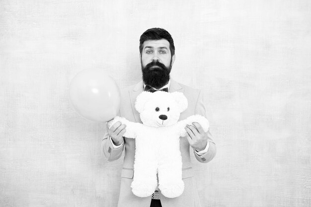 Man wear tuxedo bow tie womens day stereotype of romantic\
holidays valentines day romantic man with teddy bear and air\
balloon waiting girlfriend romantic gift macho ready romantic\
date